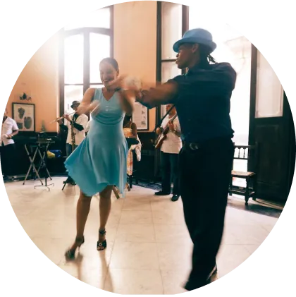 A man and woman elegantly dancing together in a vibrant dance hall, surrounded by colorful lights and a lively atmosphere.