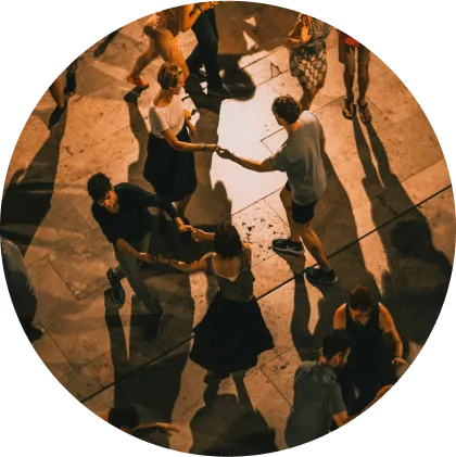 A group of people joyfully dancing in a circle on a lively street, showcasing community spirit and celebration.